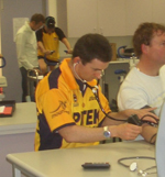 Human movement student (orange shirt foreground) and Rob Duffield (green shirt background) monitor two of the Masterfoods shift workers in Bathurst, NSW.