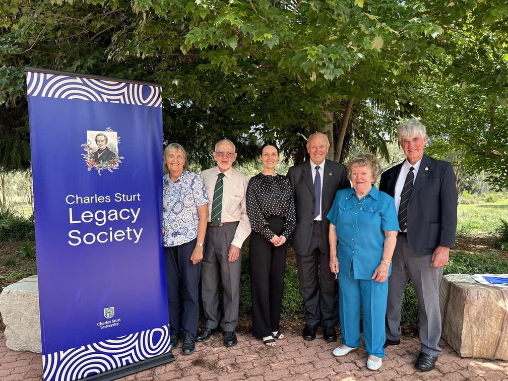 Legacy Society members pose beside a CSU banner