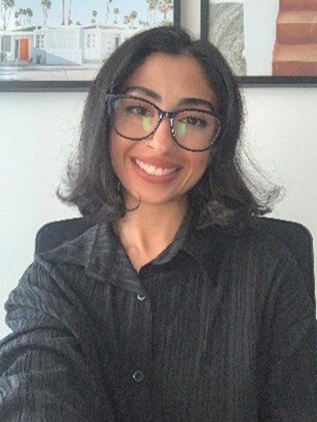 Photo of CALD Champion, Salma Arabi wearing a black shirt smiling at the camera. 