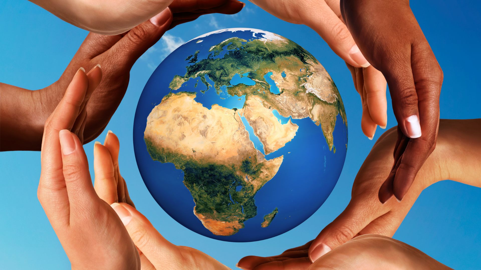  Different colored hands of several people coming together to surround the Earth, symbolizing people from different cultures interacting and communicating.