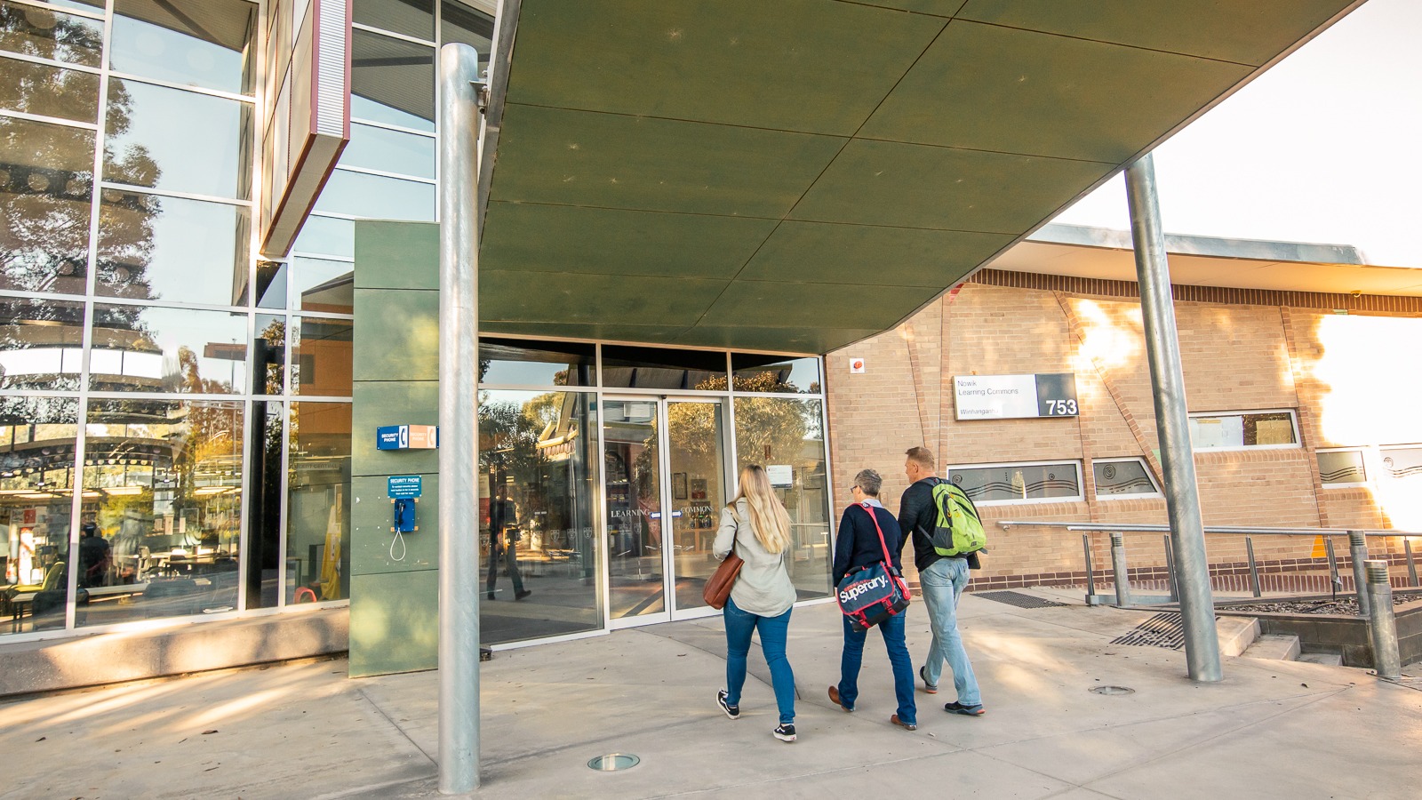 Image of three people walking towards Albury-Wodonga campus library