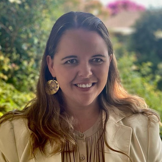 Heather McGregor in front of a garden smiling at the camera.