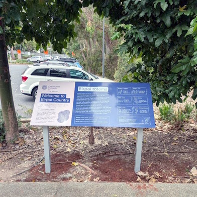 Birpai totems sign amongst a path in the trees.