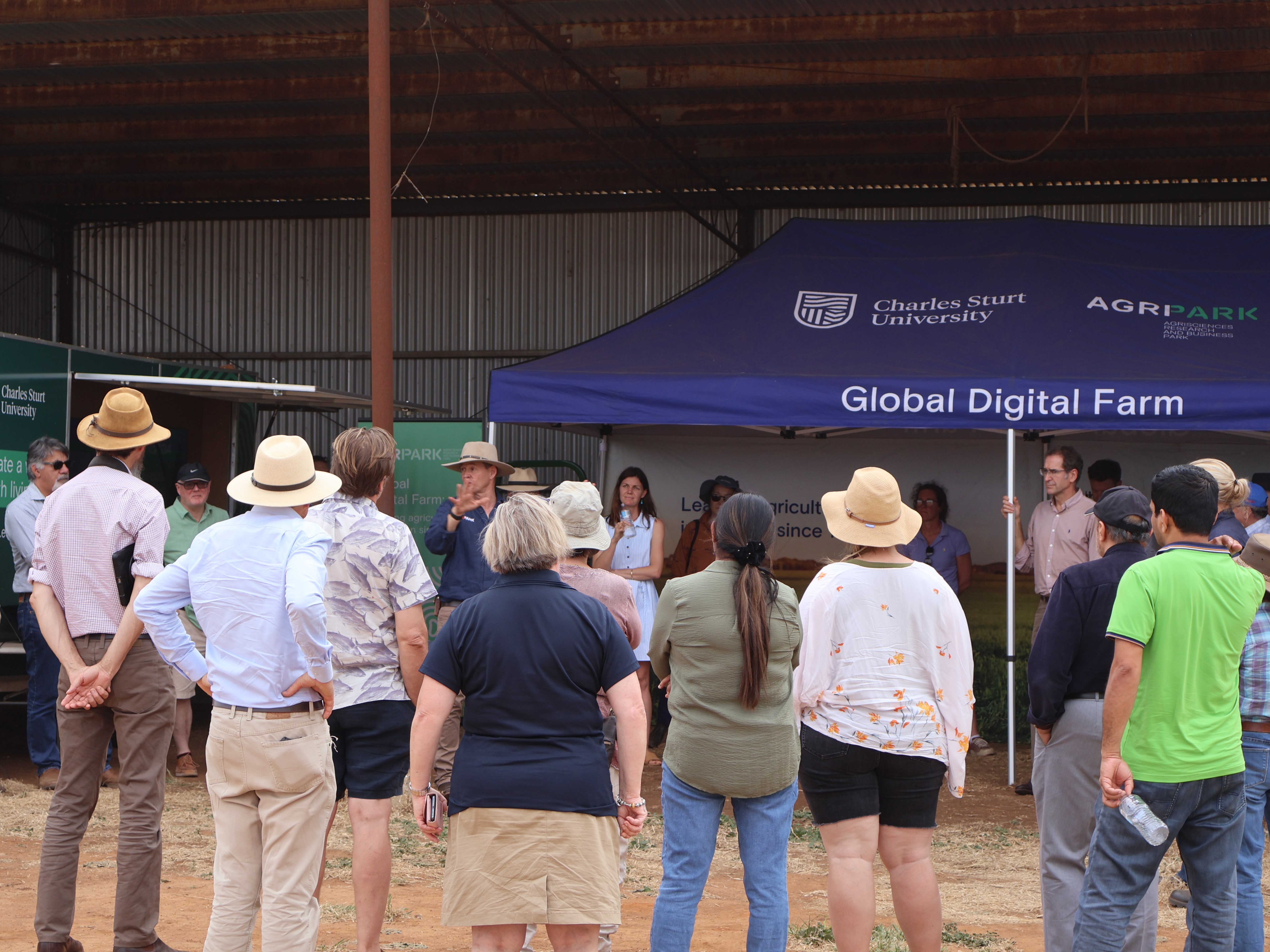 Image depicts people standing in a wool shed being shown a demonstration