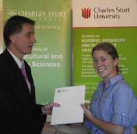 Veterinary science student Ms Emma Lee from Cobargo receives two Dean's Awards from Dean of the Faculty of Science Professor Nick Klomp.