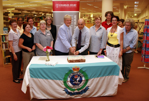 Shirley Oakley and Tony Stephenson cut the cake surrounded by Bathurst library staff